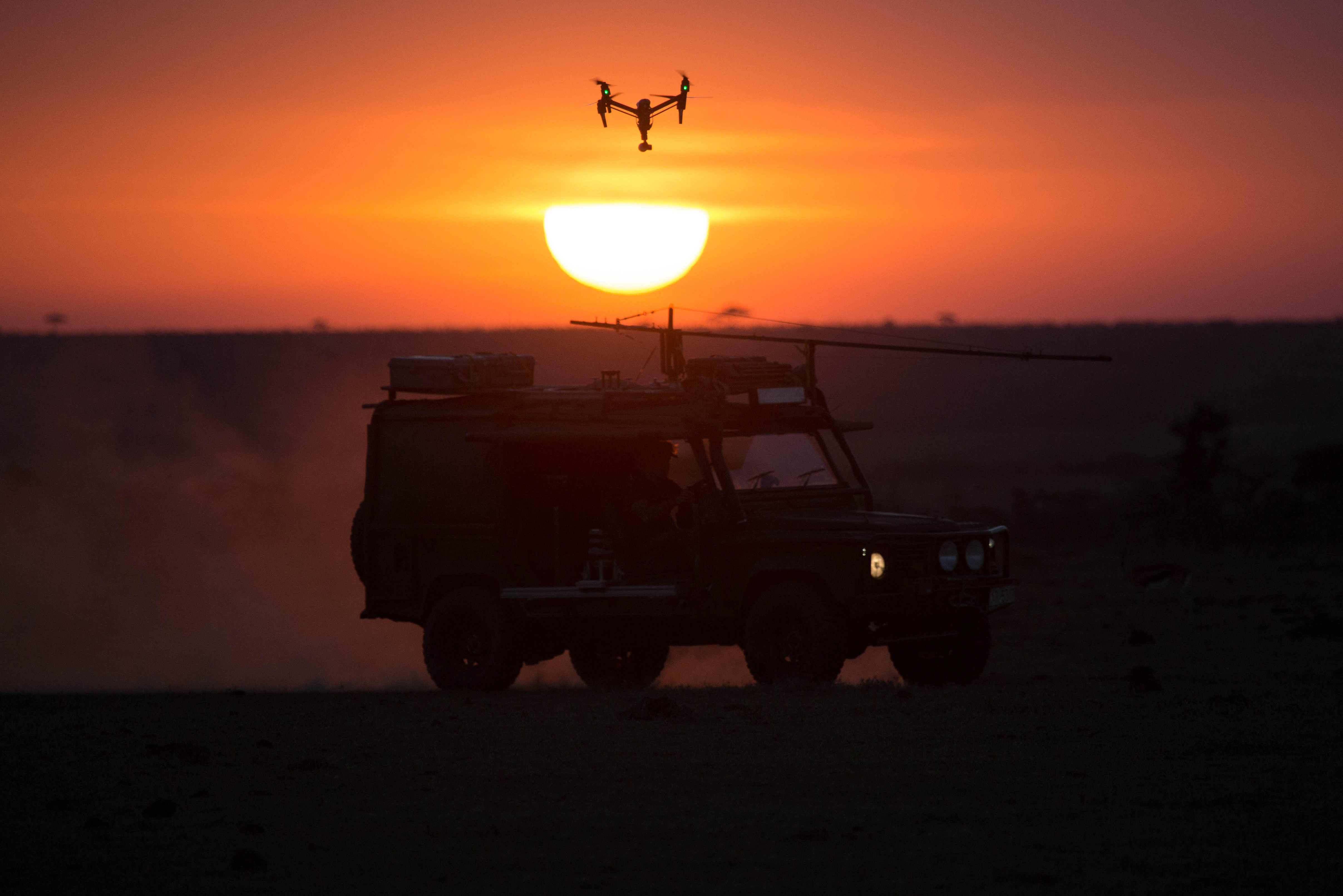 DJI Inspire 2 silhouetted against East African sunrise above a kitted Land Rover Defender
