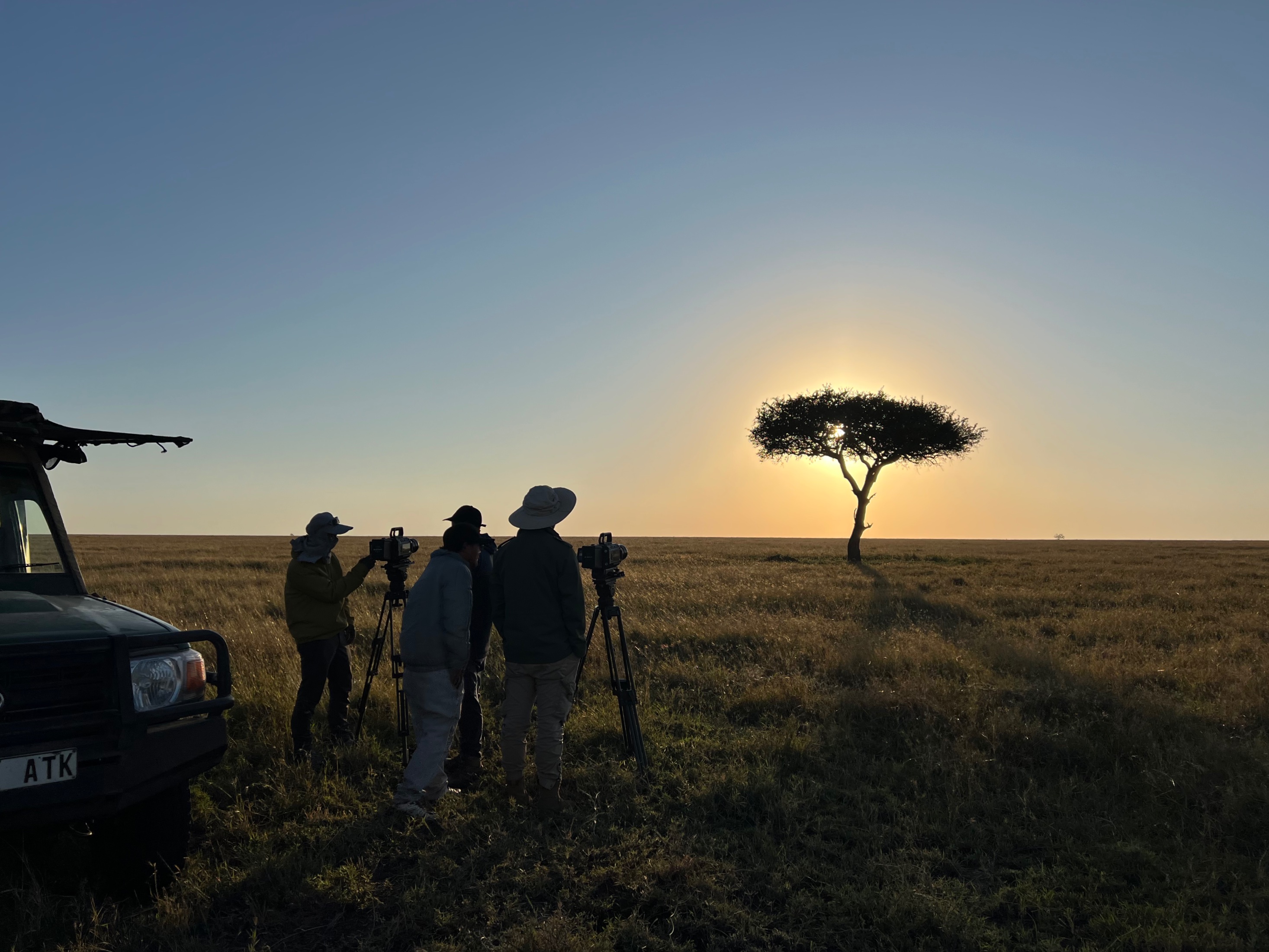 Crew with tripod-mounted cinema kit on the Maasai Mara at sunrise