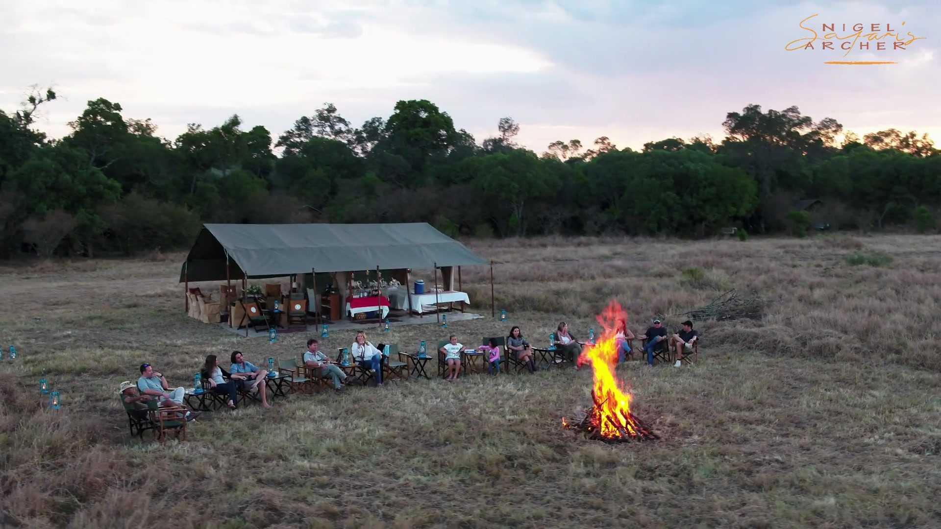 Safari camp with crew around the campfire at dusk on the Mara